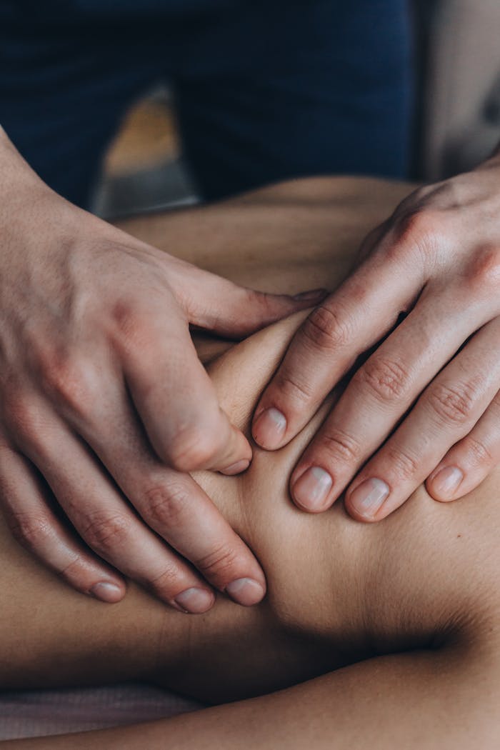 Over mij Close-up of hands giving a therapeutic massage on a person's shoulder, promoting relaxation.